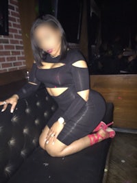 a woman in a black dress sitting on a couch